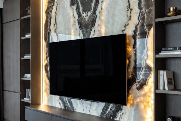 A stunning luxury TV wall in a high-end living room featuring a large flat screen television mounted flush on a dramatic floor-to-ceiling fluted walnut panel with warm LED backlighting, integrated floating shelves with curated decor and premium materials creating an ultra sophisticated and cinematic home entertainment focal point.