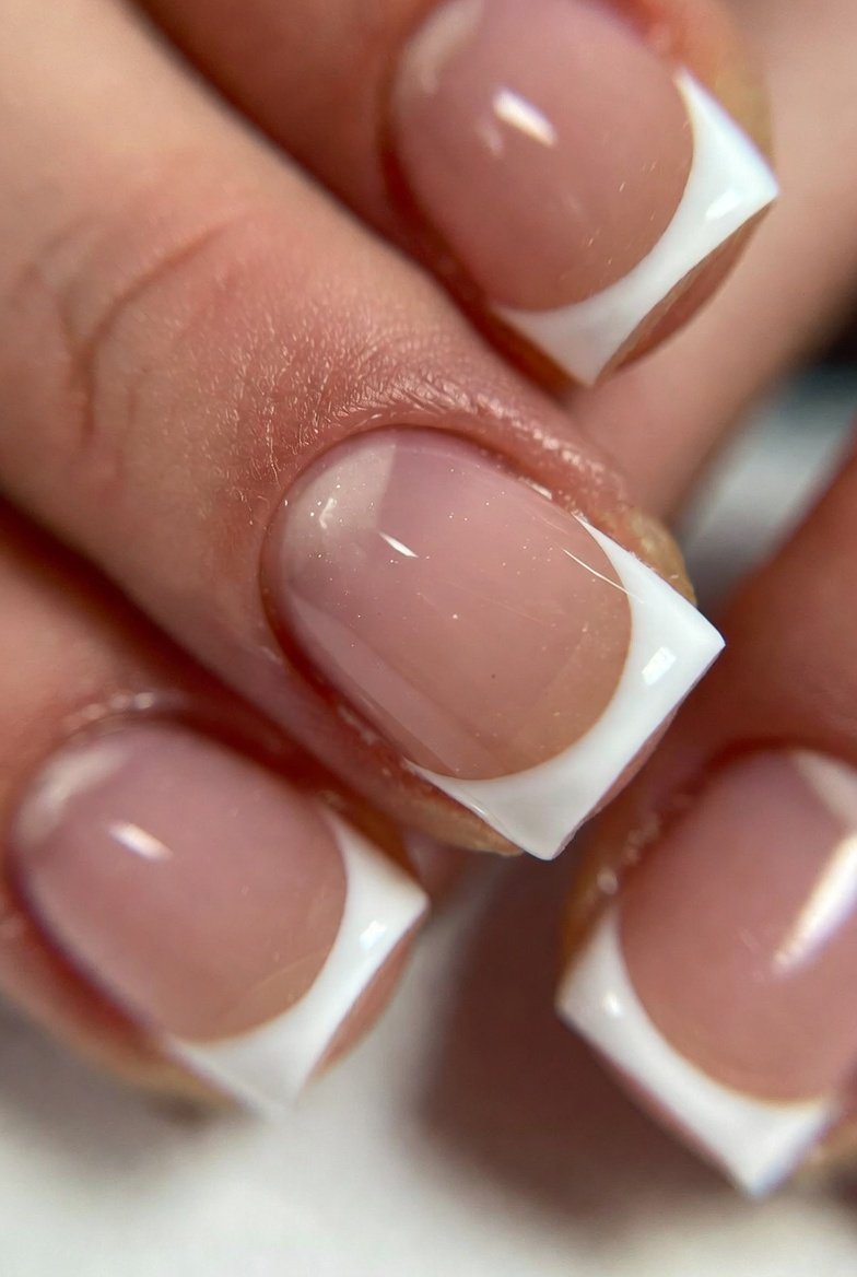 A stunning close-up of short gel nail designs featuring ultra-thin minimalist French micro-tips with a hairline white tip on natural short nails, clean barely-there elegance, soft natural lighting, professional nail art photography, ultra-realistic 8K, short gel nail designs