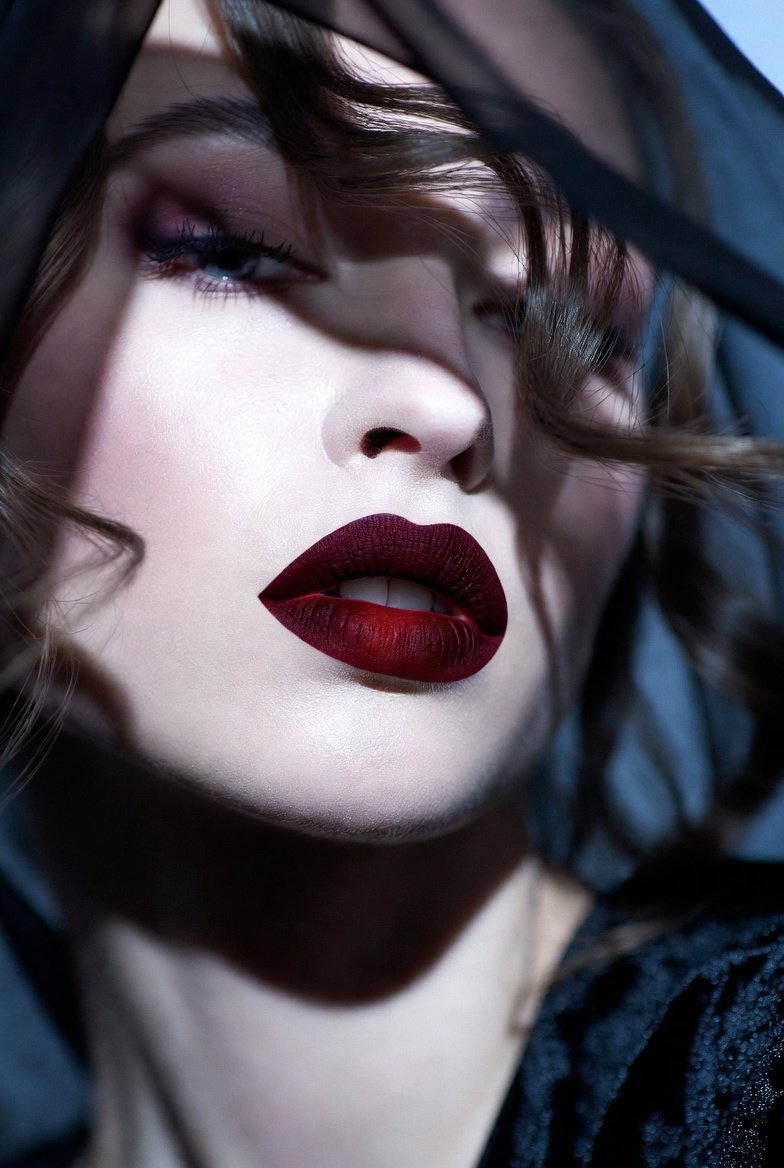 A breathtakingly dramatic collection of 14 dark feminine makeup ideas showcasing a mysteriously beautiful woman with deep velvet vampire lips smudged kohl waterline and ash grey smoky eyes representing the full range of bold and alluring dark feminine beauty looks from glossy black lids and oxblood gradient stains to pewter foil creases bruised mauve undereyes and blood red inner corners for unleashing your most powerful and goddess-like inner allure.