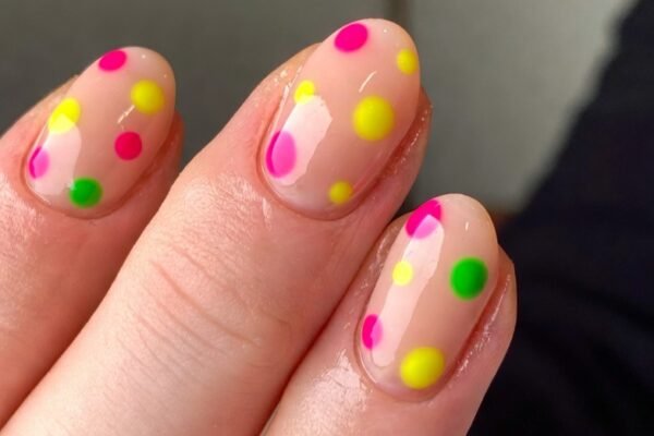 A close-up of sixteen playfully designed simple funky nails showcasing neon dots on nude base, mismatched pastel squiggles, checkerboard accents, smiley face ring fingers, splatter paint effects, and graffiti initials on short well-groomed nails — the ultimate funky nail art inspiration for adding a bold and creative pop of personality to your everyday look.