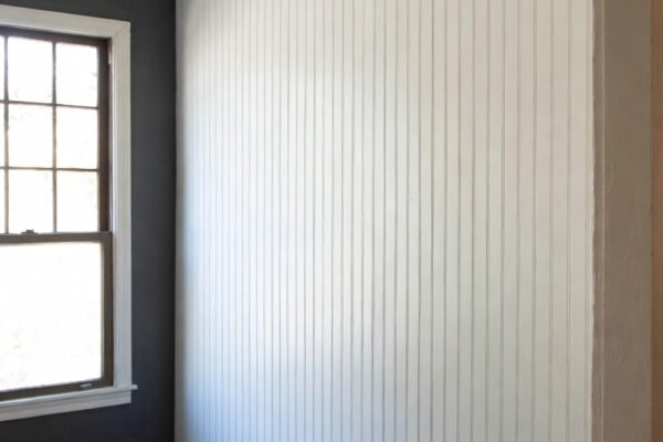 A stunning home interior transformation showcasing a classic white 24 bead board wall installation in a bright living room, highlighting timeless charm, durability, and elegant DIY home improvement design.2 / 2