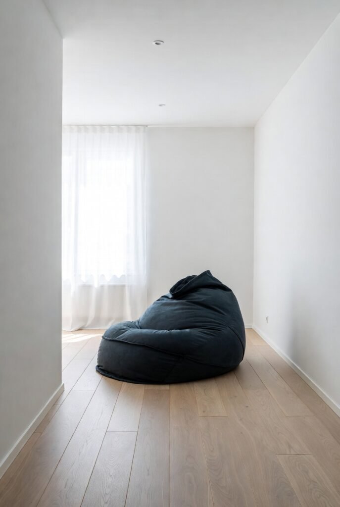 A single large premium bean bag as a bold statement piece in a clean minimalist living room, one accent color against white walls, natural daylight, architectural interior photography, negative space composition, sleek and sophisticated, editorial magazine style, ultra-HD.
