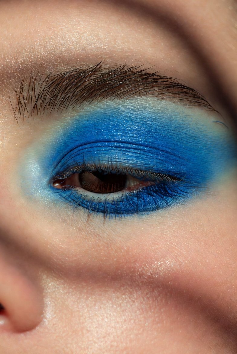 Close-up beauty shot of a model showcasing stunning blue eyeshadow looks including soft sky wash, cobalt cat-eye, navy smoky eye, turquoise pop, and sapphire shimmer cut crease, perfect inspiration for bold dreamy and unexpected blue eyeshadow styles