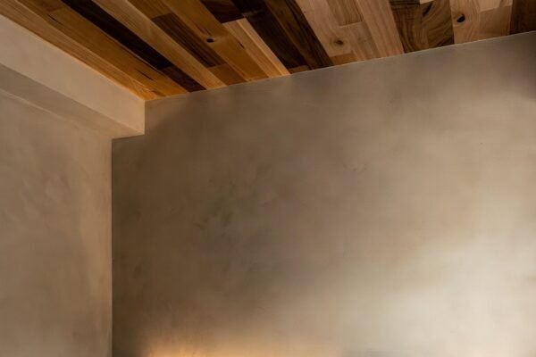 A beautifully designed 13 wood ceiling bedroom featuring mixed natural wood species on the ceiling, warm ambient lighting, neutral walls, and minimalist decor creating a cozy and natural sleep sanctuary.