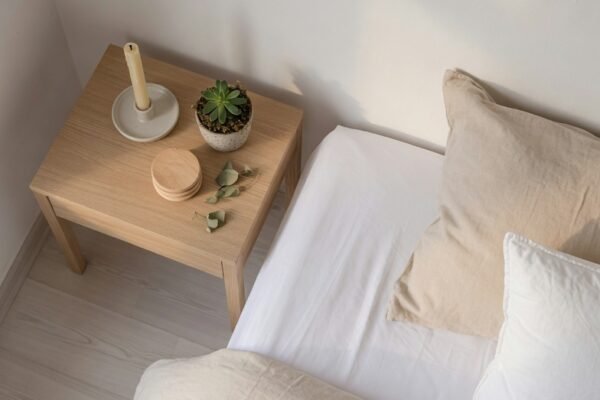 A serene minimalist bedroom with a low platform bed dressed in crisp white linen, a single potted plant, and warm morning sunlight streaming through sheer curtains, representing the ultimate guide to a bedroom minimalist transformation.